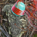 Pink, brown, orange and white telephone wire basket in progress, on a lichen-covered rock at Whalers Lookout, Tasmania.