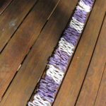 Coils of white and purple telephone wire arranged in a row of alternating bands on a wooden table.