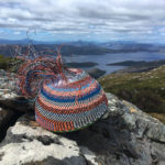 A wire basket in progress on a large boulder with the Lake Pedder impoundment in the distance.